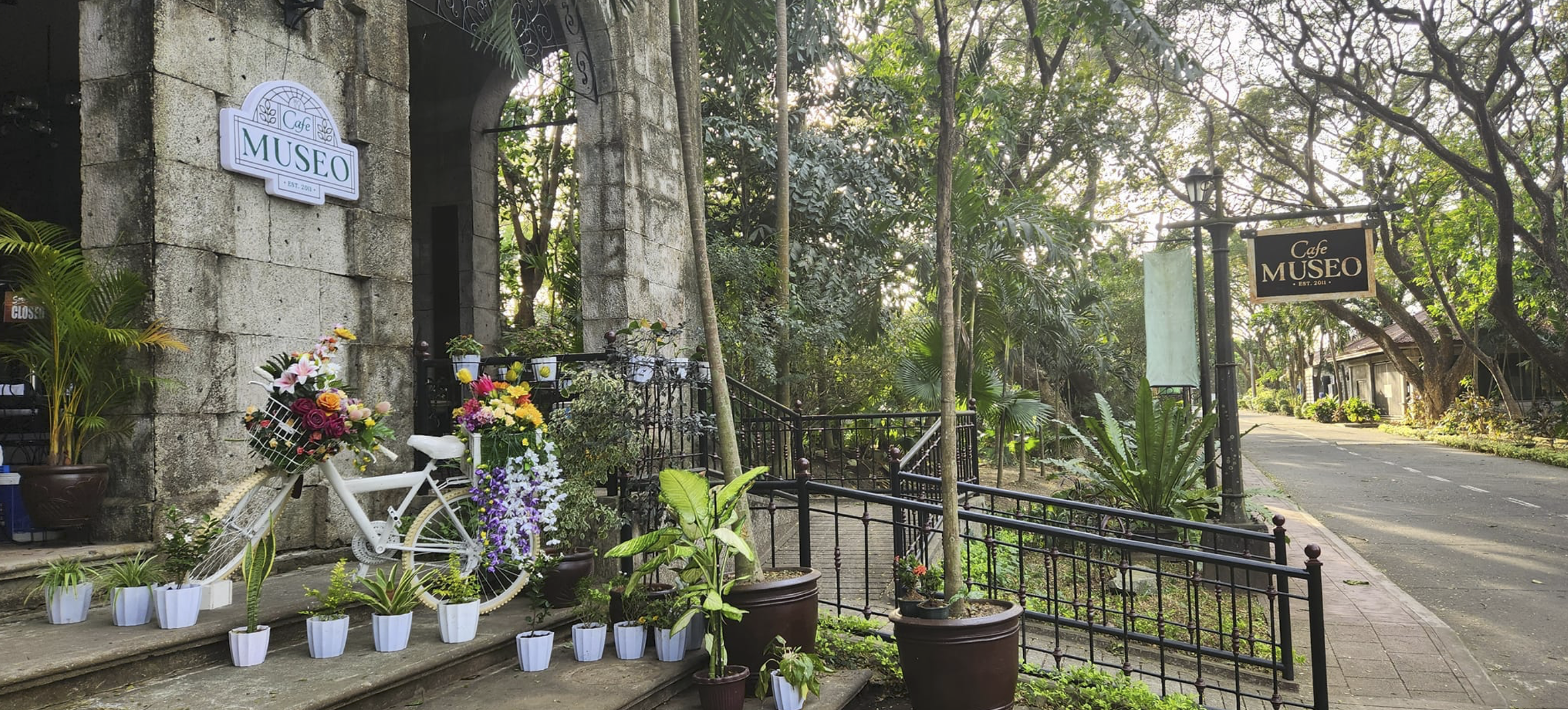 Outdoor cafe dining area beside a calm lake surrounded by lush greenery